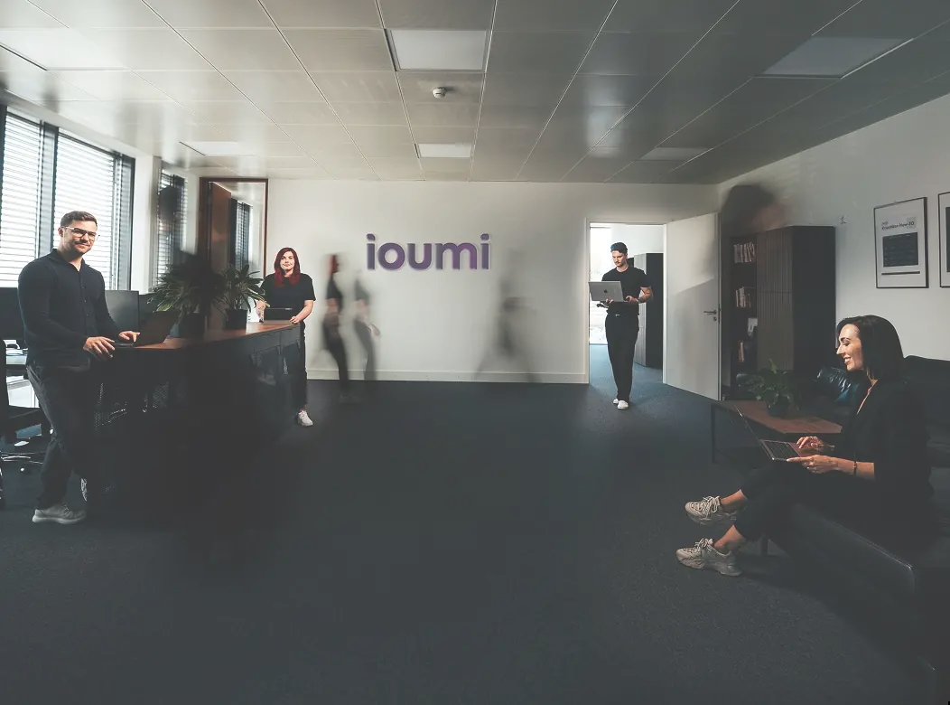 Das ioumi-Team im Büro vor dem ioumi-Logo